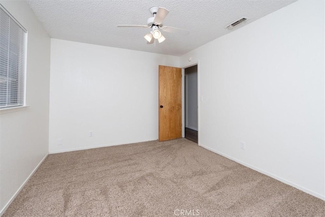 carpeted empty room with ceiling fan and a textured ceiling