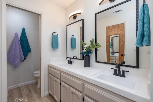 bathroom with hardwood / wood-style floors, vanity, and toilet