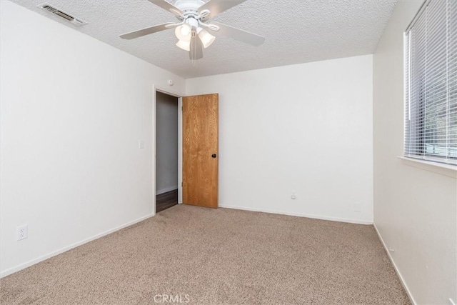 carpeted empty room with a textured ceiling and ceiling fan