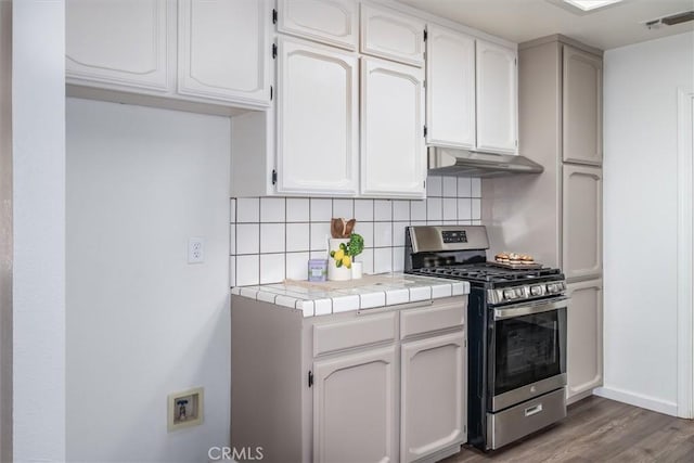 kitchen with tile countertops, stainless steel range with gas cooktop, hardwood / wood-style floors, and white cabinets