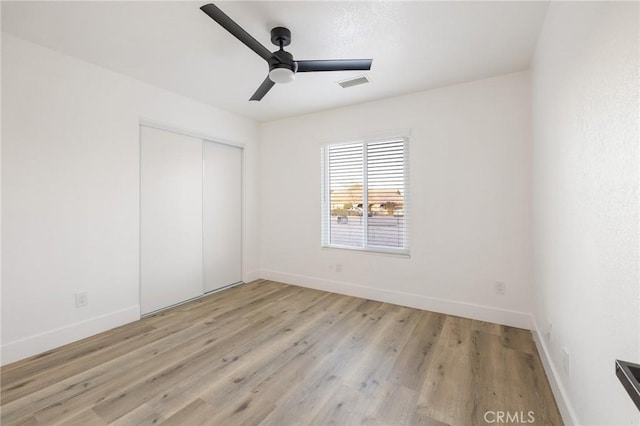 unfurnished bedroom with light wood-style flooring, visible vents, baseboards, and a closet