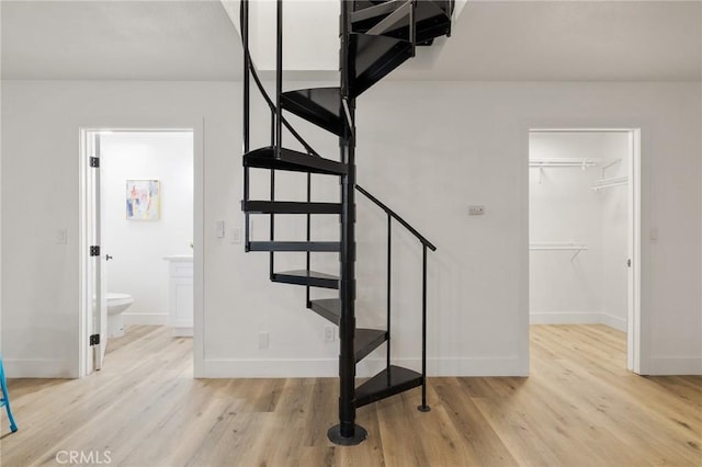 staircase featuring wood finished floors and baseboards