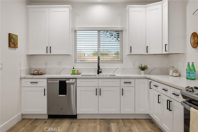 kitchen featuring light wood-style flooring, light stone counters, stainless steel appliances, white cabinetry, and a sink