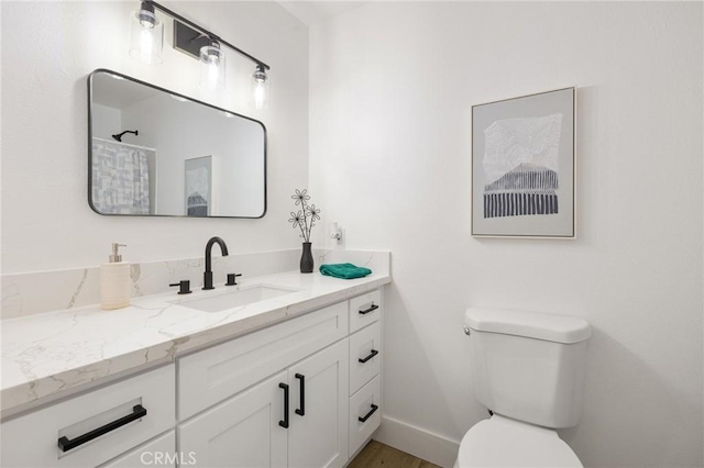 full bathroom with toilet, baseboards, and vanity