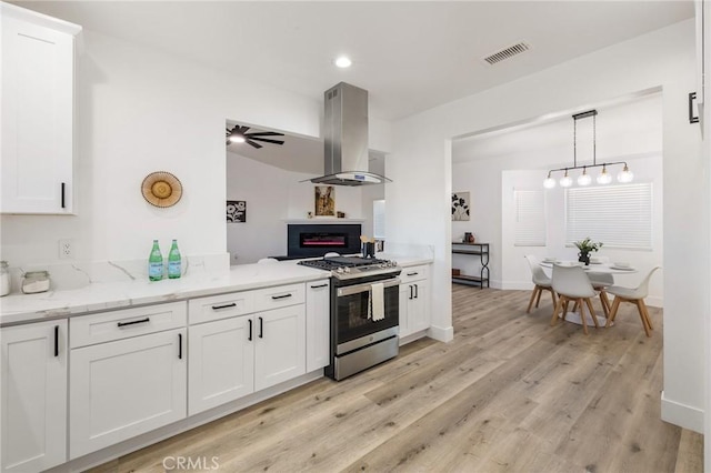 kitchen with visible vents, white cabinets, light wood-style floors, island exhaust hood, and gas range