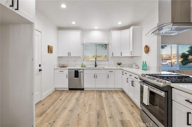 kitchen with wall chimney exhaust hood, appliances with stainless steel finishes, a sink, and recessed lighting