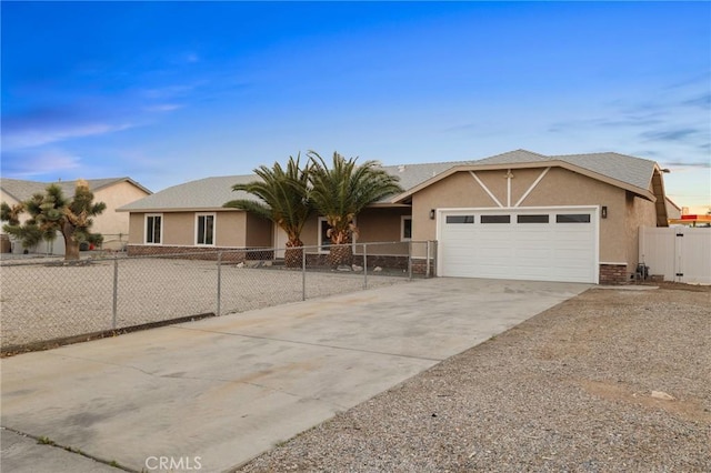 ranch-style home featuring a fenced front yard, driveway, an attached garage, and stucco siding