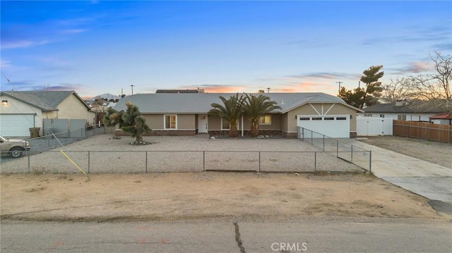 ranch-style home featuring a fenced front yard, concrete driveway, and an attached garage