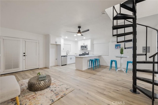 kitchen with a breakfast bar, light wood-style flooring, appliances with stainless steel finishes, white cabinetry, and a peninsula