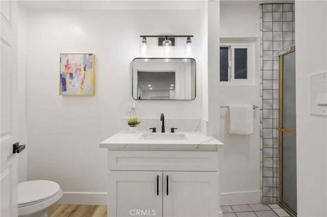 full bath featuring toilet, a stall shower, baseboards, and vanity