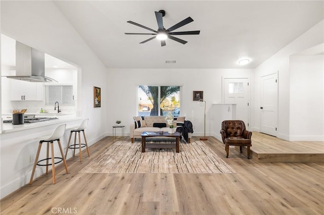 living room with light wood-style floors, lofted ceiling, baseboards, and a ceiling fan