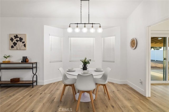 dining space with light wood-type flooring and baseboards