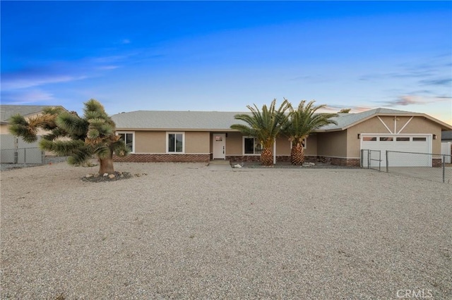 view of front of house with driveway, a garage, fence, and stucco siding