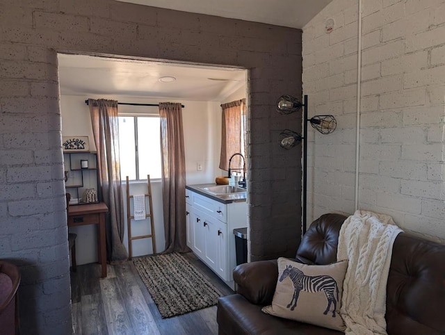 bathroom featuring wood-type flooring, brick wall, walk in shower, and vanity