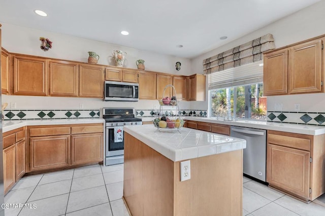 kitchen featuring a center island, stainless steel appliances, tasteful backsplash, and light tile patterned flooring