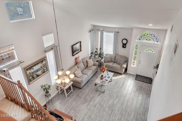 living room featuring high vaulted ceiling, light hardwood / wood-style floors, and an inviting chandelier