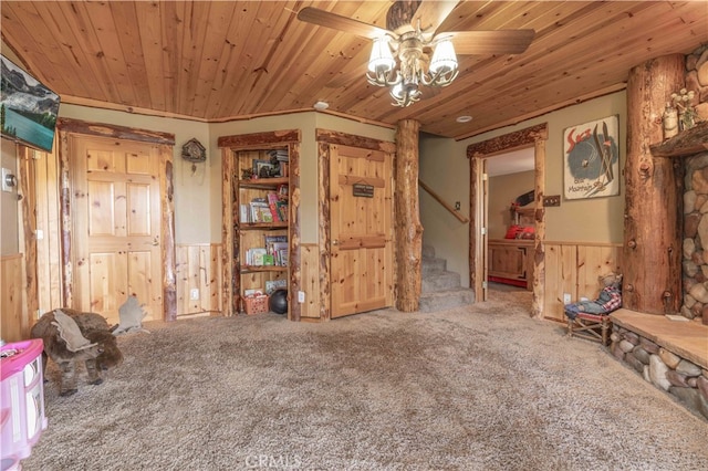 interior space featuring wood walls, wooden ceiling, and ceiling fan