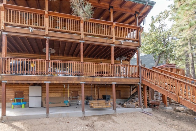 back of house featuring a wooden deck and a patio