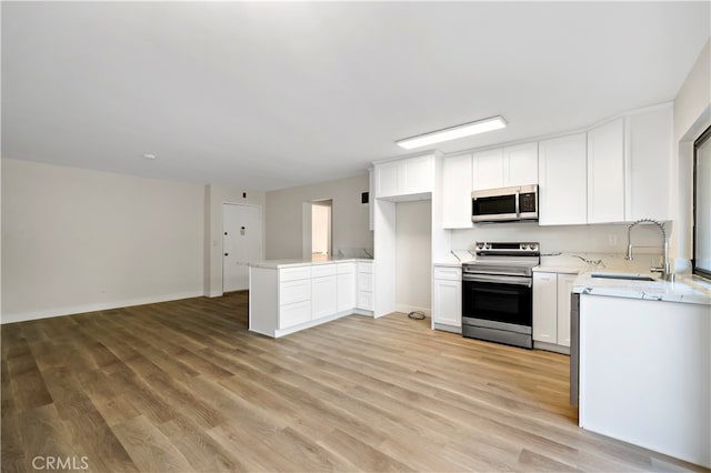 kitchen with sink, appliances with stainless steel finishes, light hardwood / wood-style floors, and white cabinetry