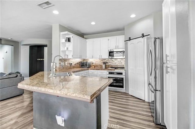 kitchen with kitchen peninsula, sink, stainless steel appliances, and light hardwood / wood-style floors