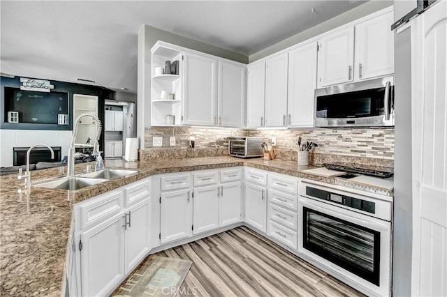 kitchen featuring a barn door, light wood-type flooring, appliances with stainless steel finishes, tasteful backsplash, and white cabinetry