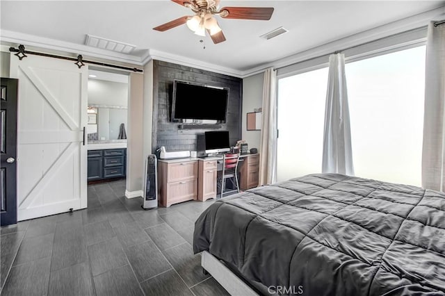 bedroom with a barn door, ensuite bath, ceiling fan, and crown molding