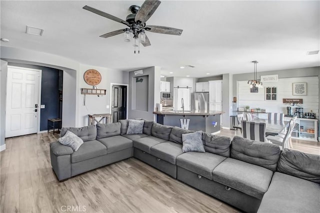 living room with ceiling fan, light wood-type flooring, and sink