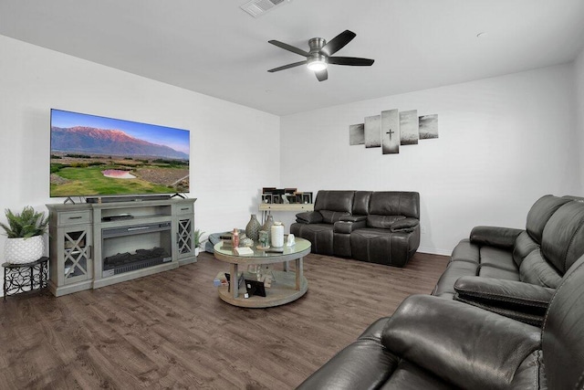 living room featuring ceiling fan, dark hardwood / wood-style floors, and a fireplace