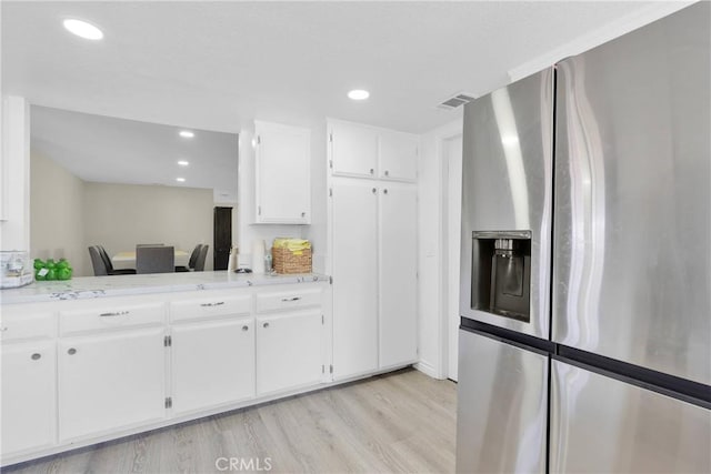 kitchen with white cabinets, light hardwood / wood-style floors, light stone counters, and stainless steel refrigerator with ice dispenser