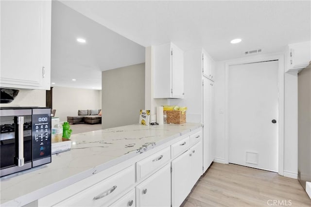 kitchen with white cabinetry, light hardwood / wood-style flooring, and light stone counters