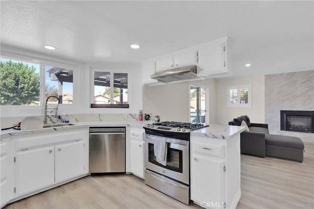 kitchen with kitchen peninsula, appliances with stainless steel finishes, white cabinets, and sink