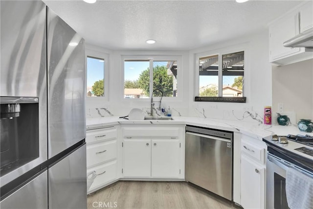 kitchen with white cabinets, a textured ceiling, stainless steel appliances, and sink