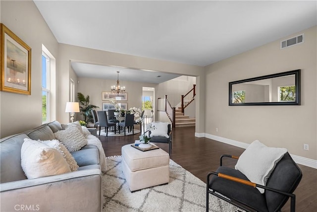 living room with a notable chandelier, a healthy amount of sunlight, and dark hardwood / wood-style flooring