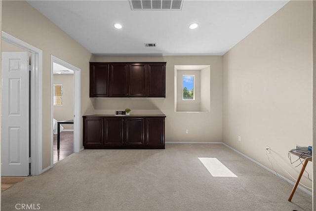 bar featuring light colored carpet and dark brown cabinetry