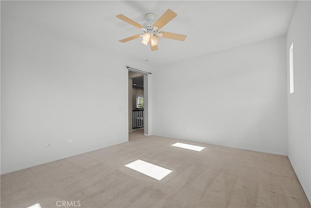 carpeted spare room featuring ceiling fan