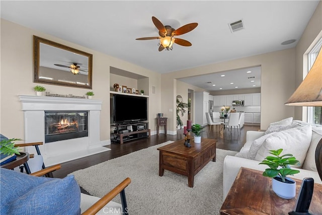 living room featuring built in features, ceiling fan, and dark wood-type flooring