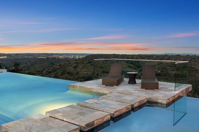 pool at dusk featuring a patio area