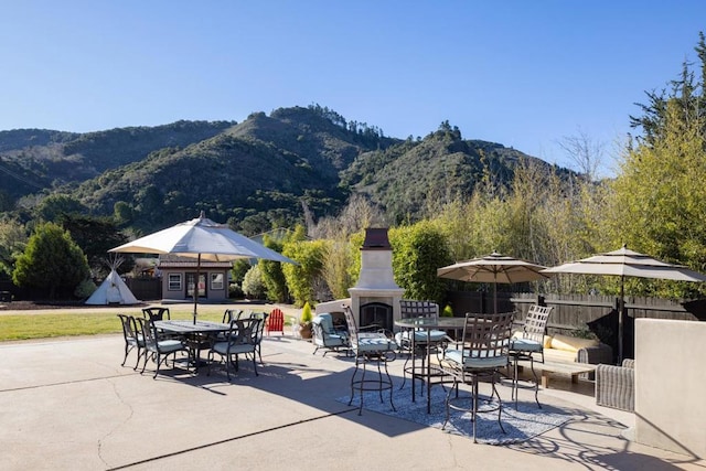 view of patio / terrace featuring a mountain view, an outbuilding, and an outdoor fireplace