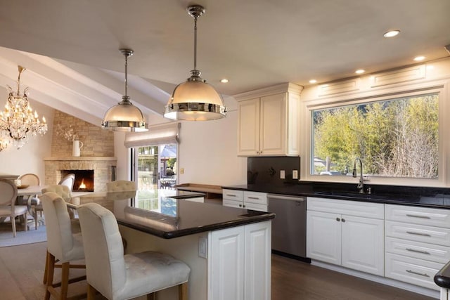 kitchen featuring dishwasher, sink, white cabinets, and a kitchen bar