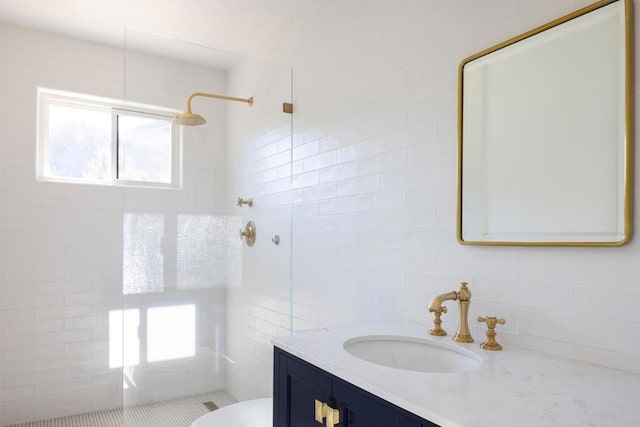 bathroom with vanity, tile walls, toilet, and tiled shower