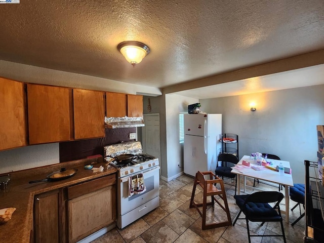 kitchen featuring range hood, white appliances, and a textured ceiling