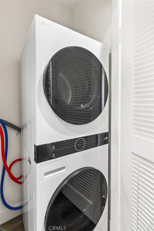 clothes washing area featuring stacked washer and clothes dryer and laundry area