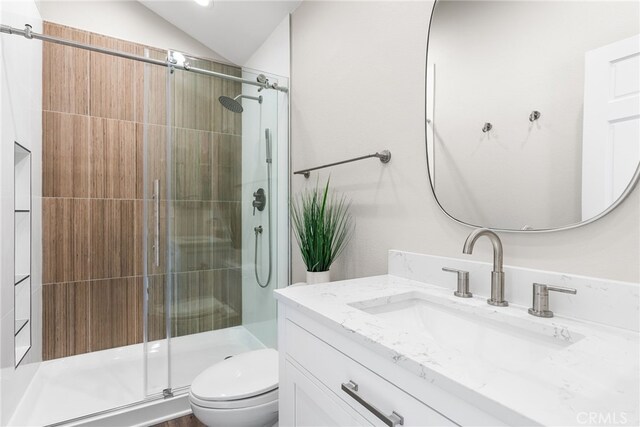 bathroom featuring lofted ceiling, vanity, a shower with door, and toilet