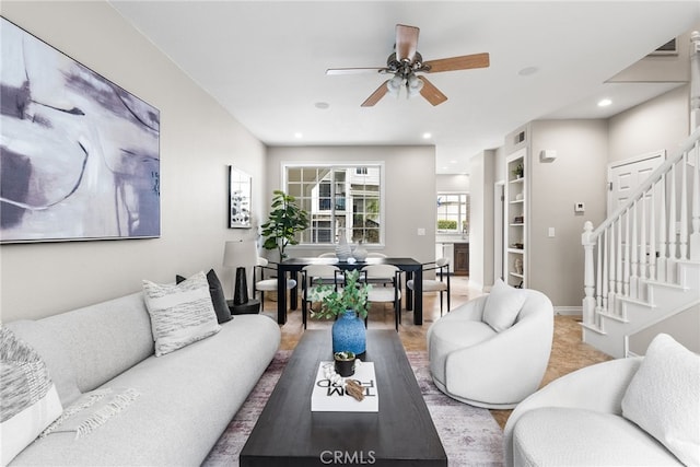 living room featuring built in shelves, recessed lighting, stairway, ceiling fan, and baseboards