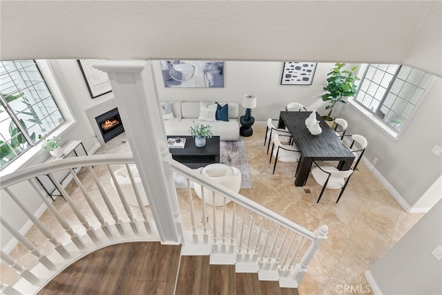 interior space with a warm lit fireplace, tile patterned flooring, and baseboards