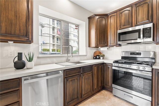 kitchen with light tile patterned floors, appliances with stainless steel finishes, sink, and dark brown cabinets