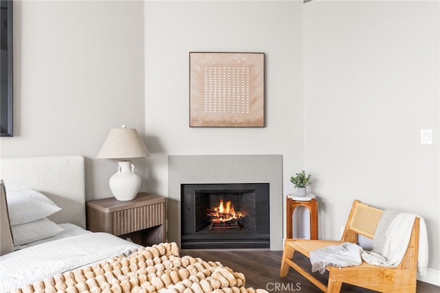 bedroom featuring a lit fireplace and dark wood finished floors