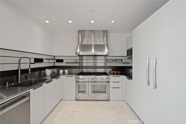 kitchen featuring light tile patterned floors, sink, wall chimney range hood, white cabinetry, and stainless steel appliances