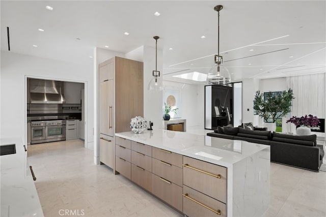 kitchen featuring pendant lighting, a skylight, light stone countertops, and light brown cabinets