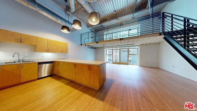 kitchen with decorative light fixtures, light wood-type flooring, a towering ceiling, dishwasher, and sink